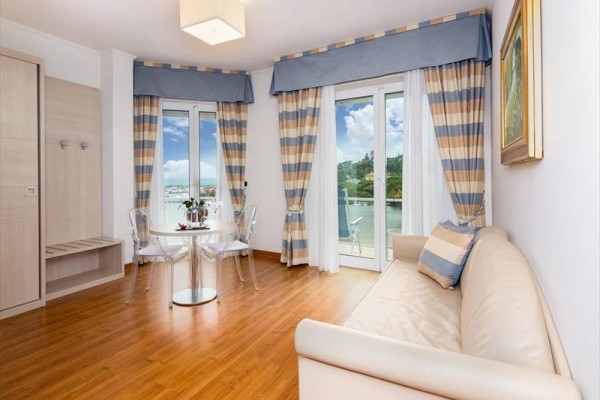 Jasny salon z kanapą, stołem i krzesłami, widok na balkon.