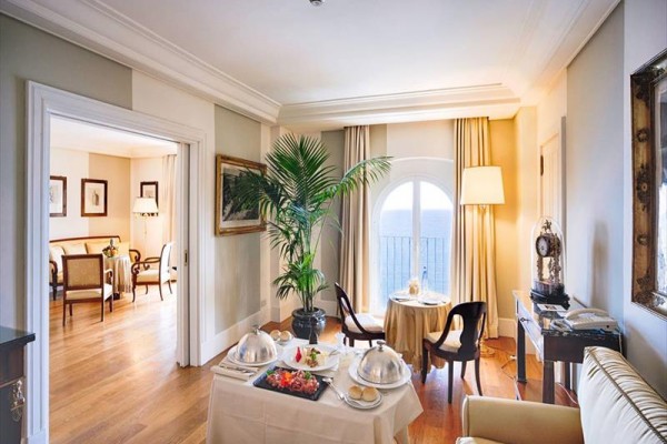 Hotelowy pokój z eleganckimi meblami i stolikiem z dwoma pokrywami na jedzenie.