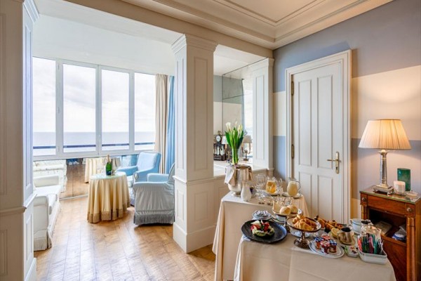 Luksusowy pokój hotelowy z widokiem na morze i stołem pełnym śniadania.