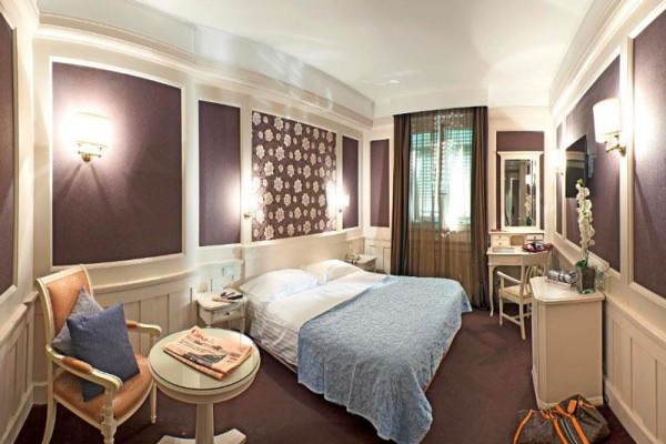 Pokój hotelowy z podwójnym łóżkiem, stolikiem, krzesłem i dekoracyjną tapetą kwiatową.