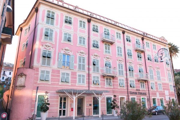Różowy budynek z napisem Hotel Europa i dekoracyjną fasadą z balkonami.