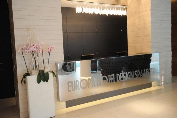 Nowoczesna recepcja hotelowa z aranżacją kwiatową i designerskim oświetleniem.  