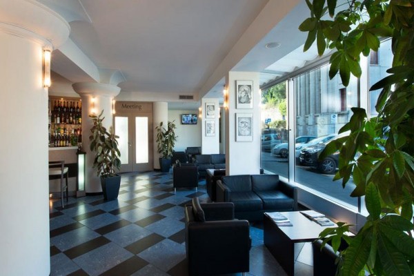 Nowoczesne lobby hotelowe z czarnymi fotelami i dużymi oknami.