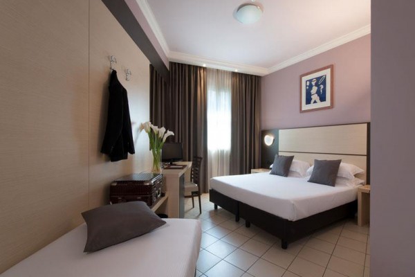Pokój hotelowy z łóżkiem małżeńskim, pojedynczym łóżkiem i biurkiem.