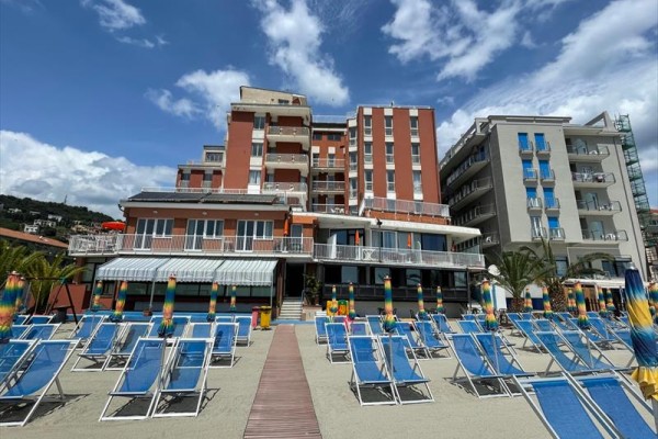 Hotel przy plaży z parasolami i leżakami.