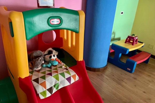 Zjeżdżalnia dziecięca z pluszowymi zabawkami i kolorowym stołem w pokoju.