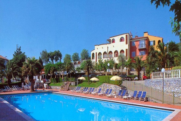 Hotel z basenem otoczonym palmami i leżakami.
