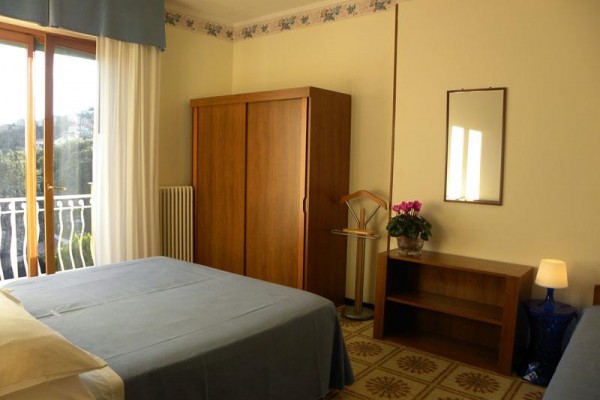 Pokój hotelowy z łóżkiem małżeńskim, szafą i balkonem.