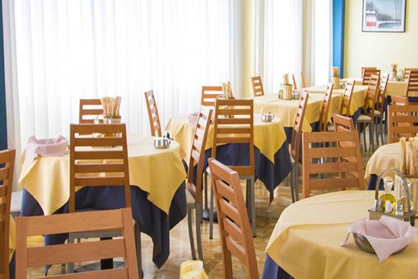 Restauracja z żółtymi obrusami na stołach i drewnianymi krzesłami.
