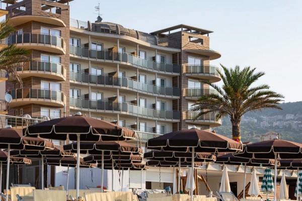 Nowoczesny hotel z balkonami i palmami przed nim.  