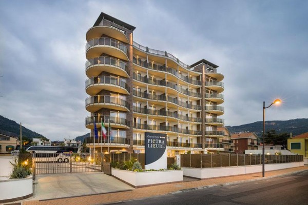 Nowoczesny wielopiętrowy hotel z balkonami i szklanymi balustradami o zmierzchu.