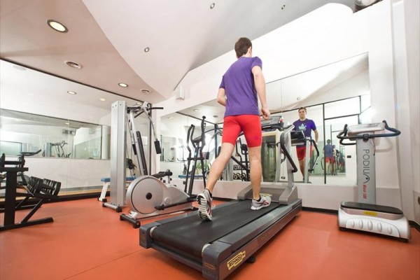 Osoba biegnie na bieżni w centrum fitness.