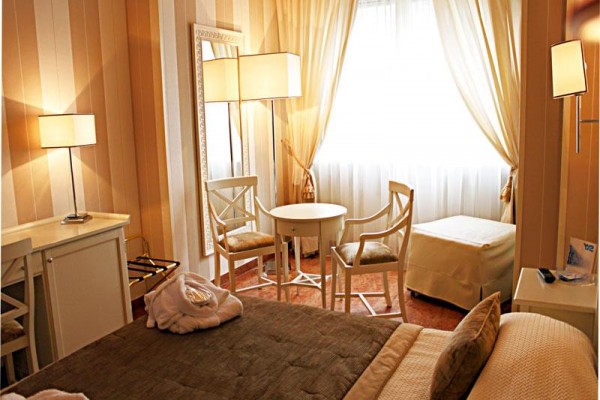 Elegancki pokój hotelowy z łóżkiem, stołem i dwoma krzesłami przy oknie.