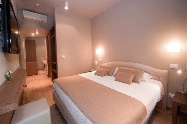 Nowoczesny pokój hotelowy z łóżkiem małżeńskim i delikatnym oświetleniem.  