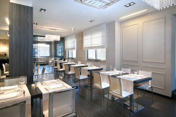 Elegancka nowoczesna restauracja z białymi krzesłami i nakrytymi stołami.