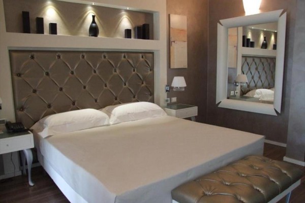 Nowoczesny pokój hotelowy z dużym łóżkiem, lustrem i elementami dekoracyjnymi.