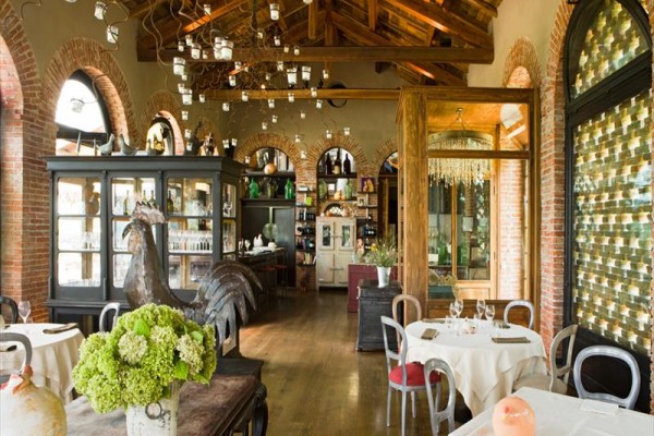 Eleganckie wnętrze restauracji z rustykalnymi ceglanymi ścianami i drewnianym sufitem.