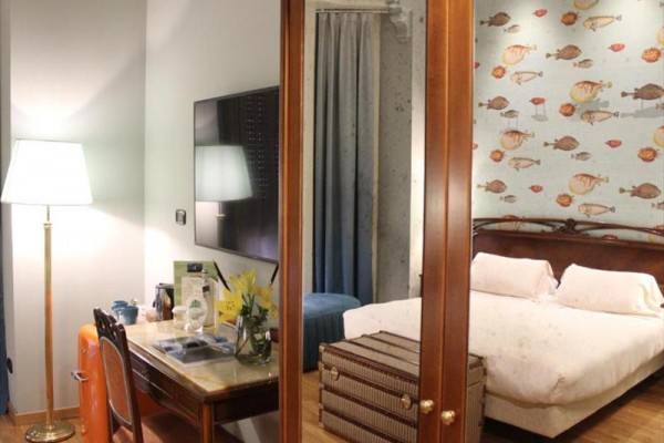 Luksusowy pokój hotelowy z łóżkiem, biurkiem i wyrazistą tapetą z motywem ryb.