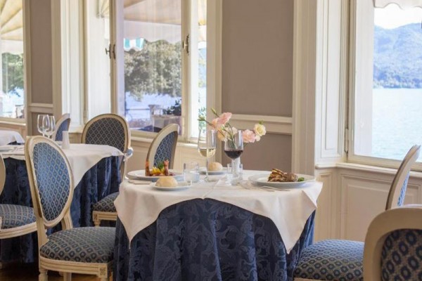 Elegancka restauracja z nakrytymi stołami przy oknie z widokiem na jezioro.
