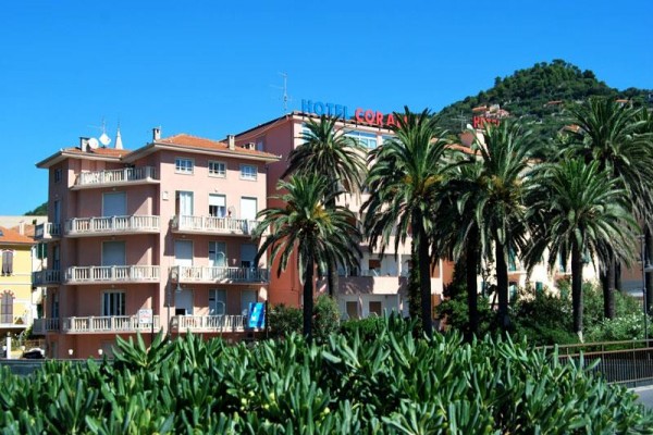 Budynek hotelu otoczony palmami z niebem w tle.