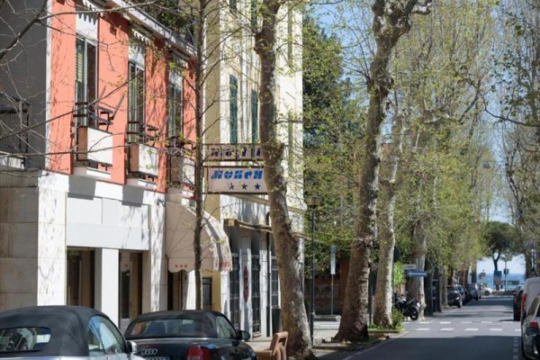 Ulica otoczona drzewami z widokiem na budynki i zaparkowane samochody.