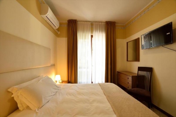 Pokój hotelowy z łóżkiem, klimatyzacją, telewizorem i zasłonami w oknie.
