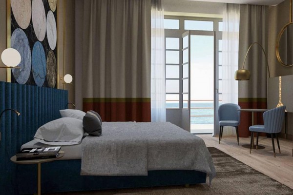 Nowoczesny pokój hotelowy z łóżkiem, krzesłem i widokiem na morze.