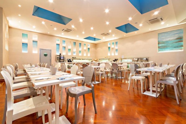 Nowoczesna restauracja z białymi stołami i plastikowymi krzesłami.
