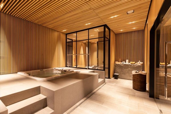 Luksusowa przestrzeń wellness z jacuzzi i drewnianą okładziną.