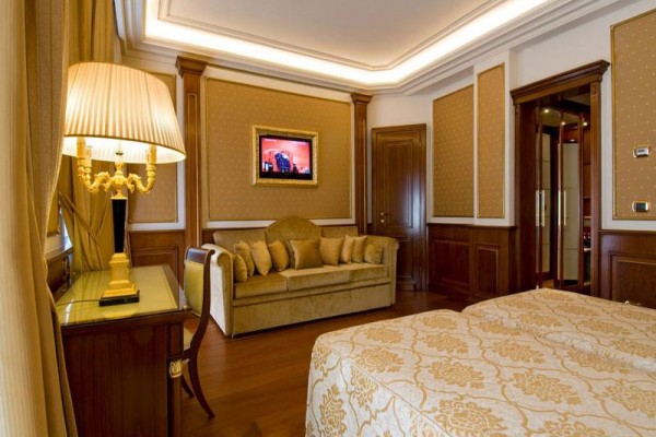 Luksusowy pokój hotelowy z sofą, łóżkiem i złotymi dekoracjami.