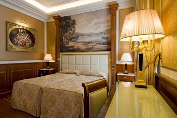 Luksusowy pokój hotelowy z łóżkiem podwójnym, lampami i malowidłami ściennymi.