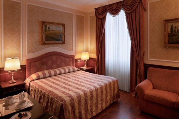 Elegancki pokój hotelowy z dużym łóżkiem i brązowymi zasłonami.
