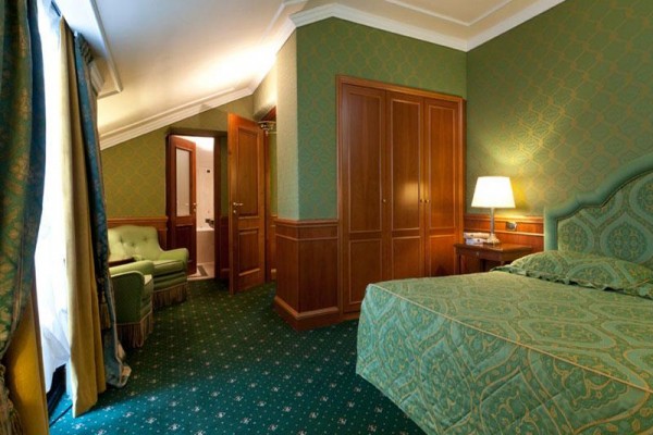 Luksusowy pokój hotelowy z podwójnym łóżkiem i zielonym wystrojem.