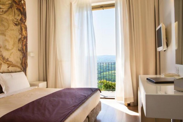 Pokój hotelowy z łóżkiem i widokiem na krajobraz za oknem.