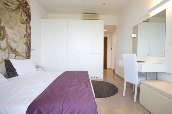 Nowoczesny pokój hotelowy z dużym łóżkiem, szafą i biurkiem.