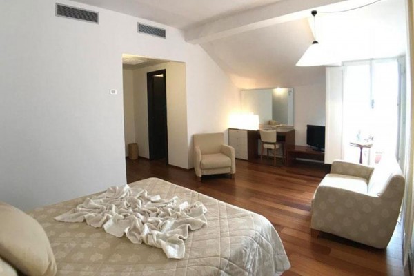 Jasny pokój hotelowy z łóżkiem, dwoma fotelami i biurkiem.