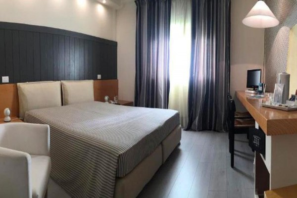 Nowoczesny pokój hotelowy z podwójnym łóżkiem, biurkiem i zasłonami przy oknie.