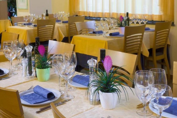 Stoliki w restauracji są elegancko nakryte z kieliszkami, talerzami i materiałowymi serwetkami.