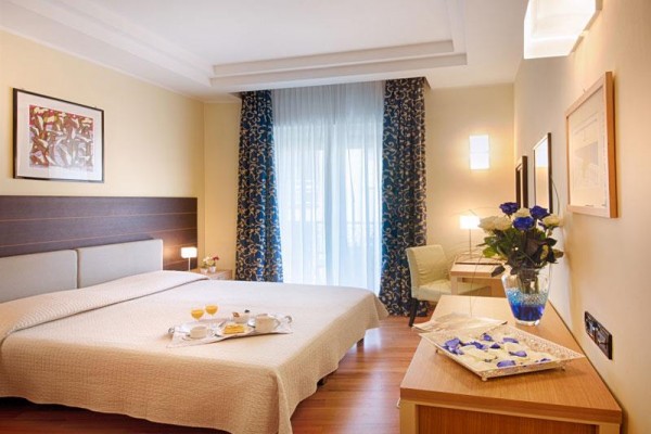 Elegancki pokój hotelowy z dużym łóżkiem, stołem i bukietem kwiatów.