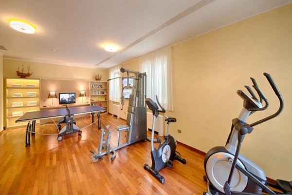 Sala fitness z urządzeniem do ćwiczeń, rowerem treningowym, stołem do pingponga i telewizorem.