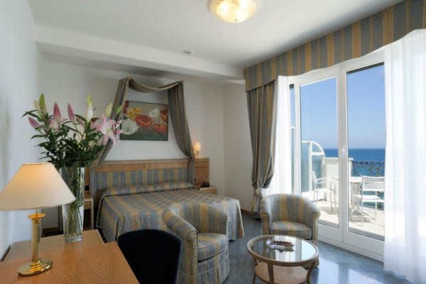 Elegancki pokój hotelowy z balkonem i widokiem na morze.