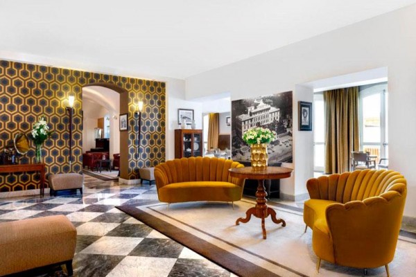 Elegancki salon z żółtymi sofami i szachownicową podłogą.