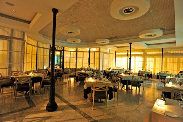 Stylowa restauracja z okrągłymi stołami i delikatnym oświetleniem.