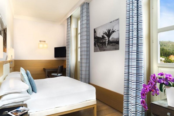 Nowoczesny pokój hotelowy z podwójnym łóżkiem, biurkiem i widokiem z dużego okna.