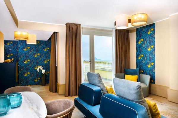 Nowoczesny salon z niebieskim i żółtym wystrojem, dużymi oknami i widokiem na balkon.