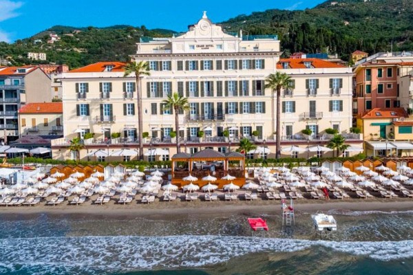 Grandhotel na wybrzeżu z leżakami i parasolami na plaży.