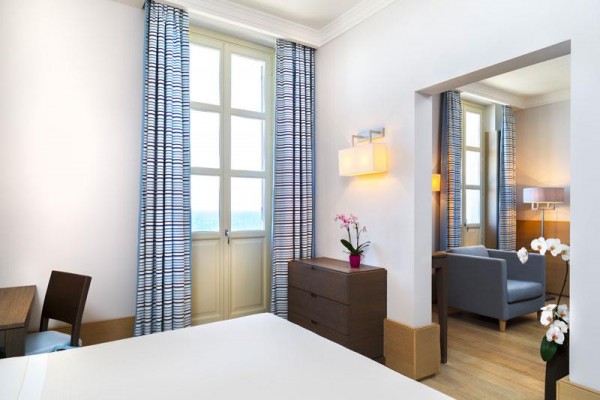 Nowoczesny pokój hotelowy z dużymi oknami i widokiem na morze.