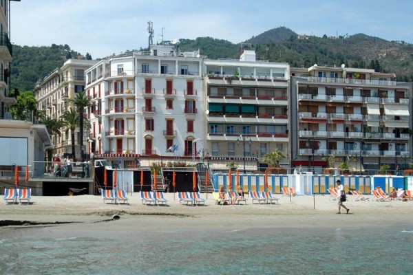 Kolorowe leżaki na piaszczystej plaży przed budynkami w nadmorskim mieście.