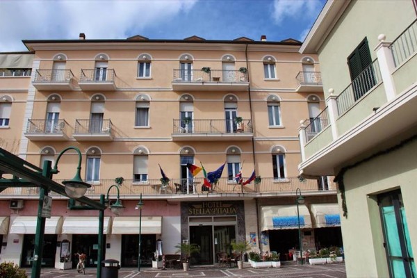 Budynek hotelu z balkonami i flagami przy wejściu.