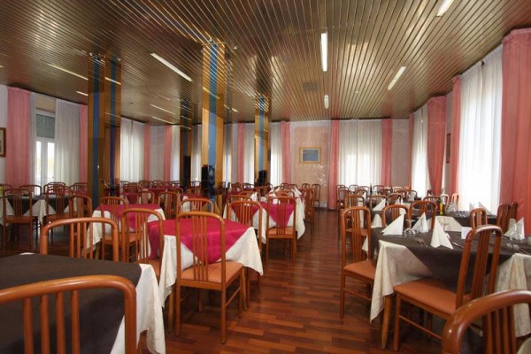 Restauracja z drewnianymi stołami, krzesłami i białymi zasłonami.